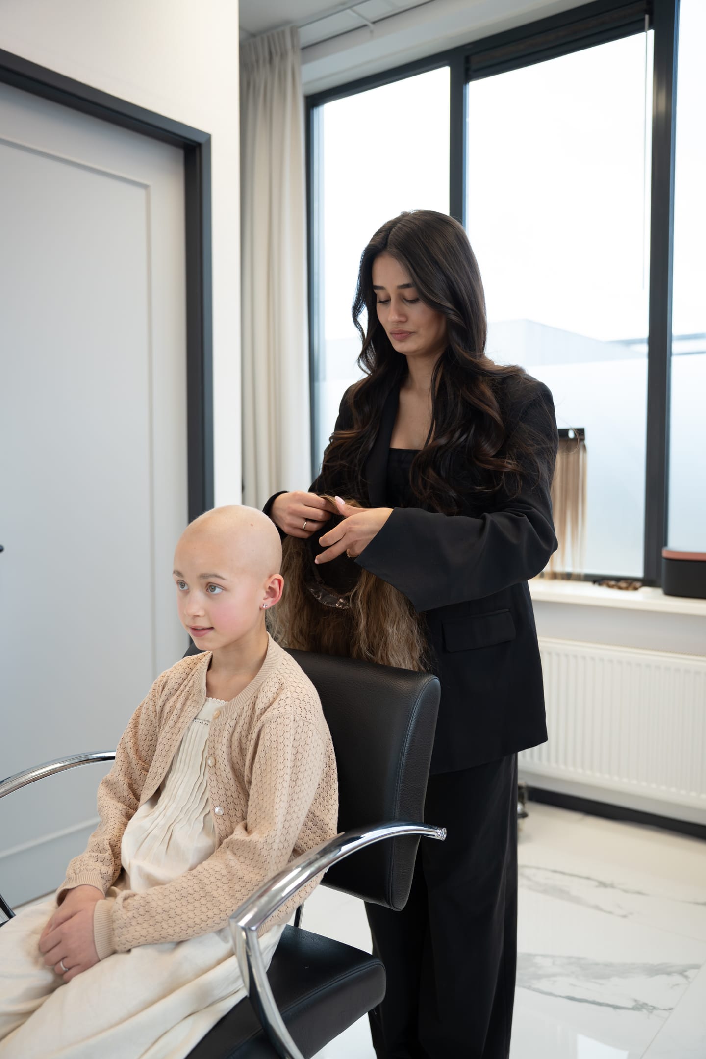 Een kind bekijkt haar nieuwe haarwerk in de salon